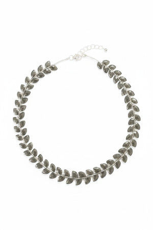 The ANN LIGHTFOOT Faceted Flat Herringbone Cut Smokey Quartz Necklace features leaf-shaped segments linked in a circular pattern, shown on a plain white background.