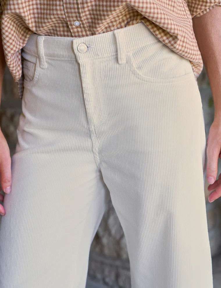 A woman wearing a tan and white gingham button-down shirt tucked into FRANK AND EILEEN - BRENNAN EVERYDAY BARREL IN ITALIAN PERFORMANCE CORDUROY VINTAGE WHITE barrel jeans.