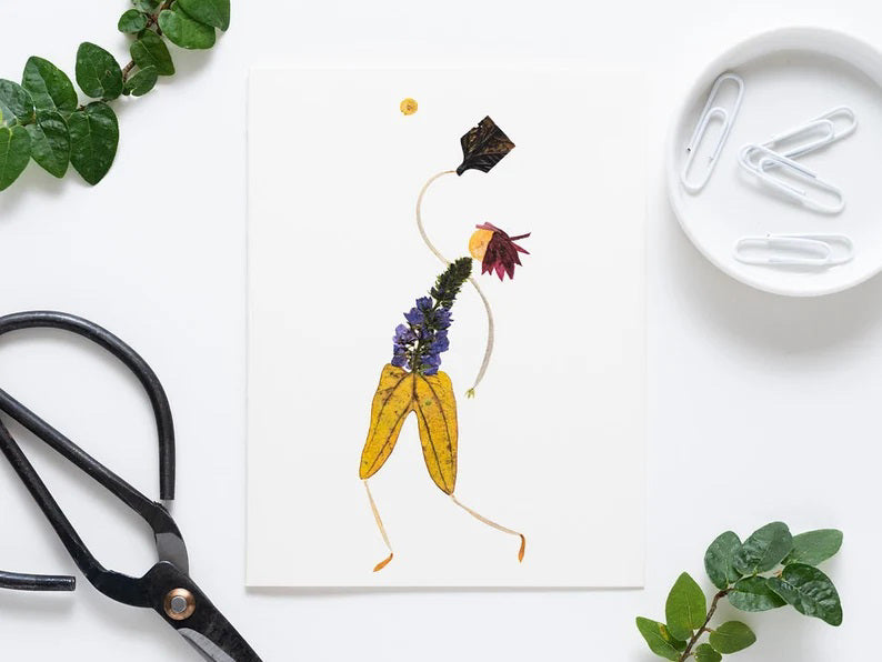 The PETAL PEOPLE PRESS - PICKLEBALL GREETING CARD by Petal People Press features a whimsical figure made of pressed flowers and leaves on a white background, posed dynamically with a black leaf racket and yellow flower ball, resembling an elegant pickleball moment.