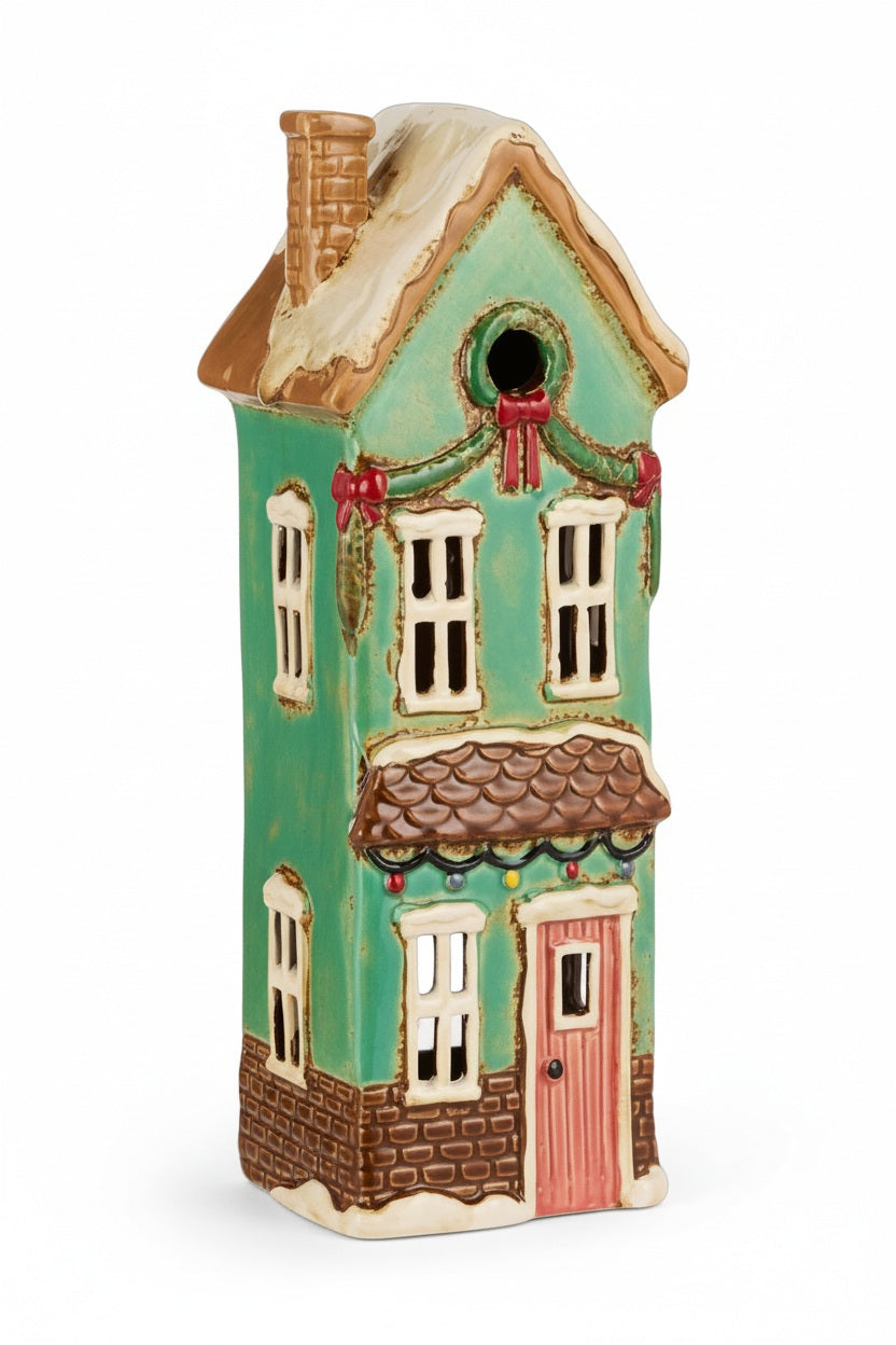 RAZ IMPORTS CERAMIC HOUSE: a tall, narrow, green clay house with a pink door and a snow-dusted roof, designed as a tealight candle holder.