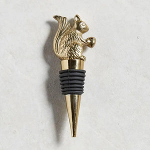 The BE HOME - SQUIRREL BOTTLE STOPPER by BE HOME, INC features a gold squirrel with an acorn atop a tapered metal base and black rubber rings—perfect for wine lovers.