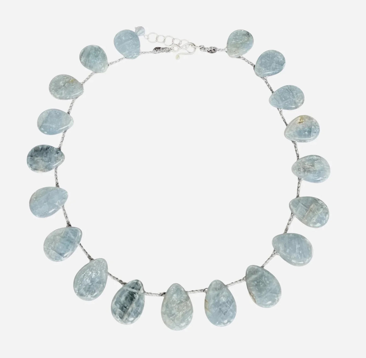 A mannequin in a textured, cream faux fur vest showcases the ANN LIGHTFOOT - BRAIDED RAS DU COU FAN CALCITE NECKLACE, featuring blue calcite stones on gold-tone links with a sterling silver clasp, against a softly lit background.