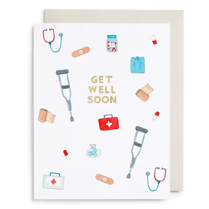The E. FRANCES - FIRST AID KIT CARD from E. FRANCES PAPER is a watercolor greeting card featuring "Get Well Soon" in gold letters, surrounded by illustrations of crutches, stethoscopes, bandages, pills, first aid kits, pill bottles, and an ice pack on a white background—thoughtfully designed as a sympathy card and proudly made in the USA.