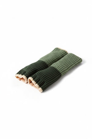 A long, ribbed knit scarf in two shades of green with a beige stripe separating them is laid out on a white background—perfect for pairing with your favorite travel-ready gloves or MERSEA’s Montauk Colorblock Fingerless Gloves in Eden for effortless seasonal style.