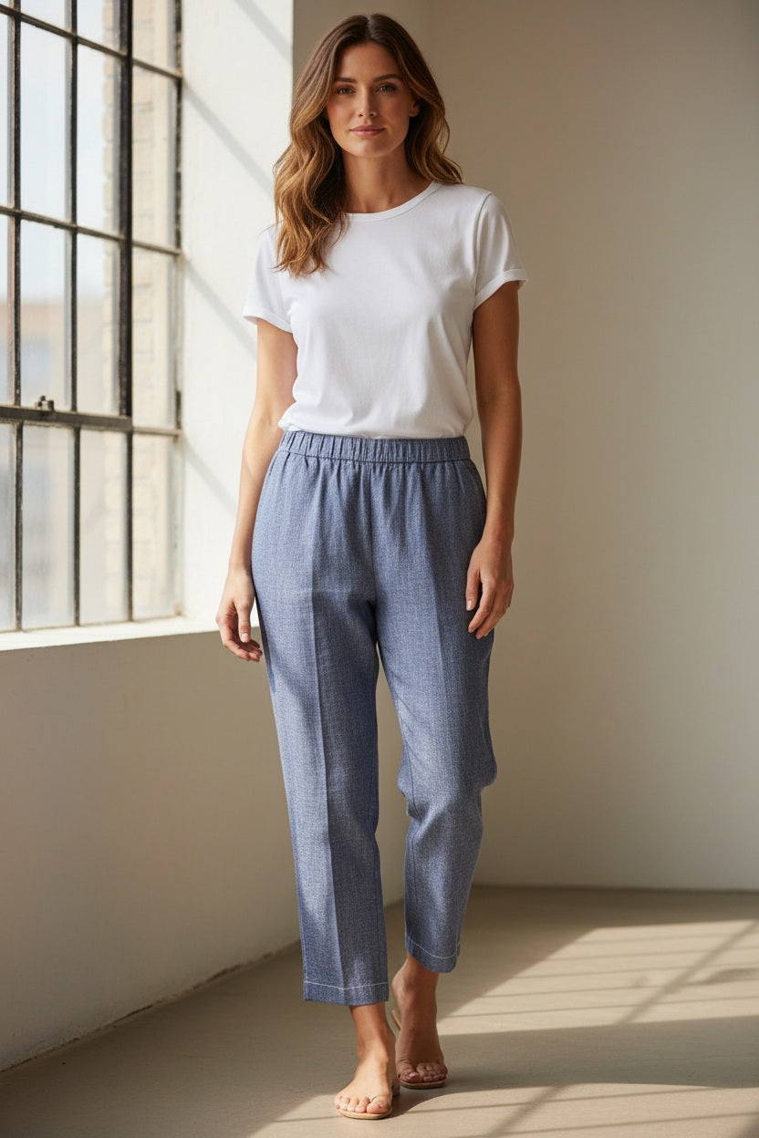 A person wears MEIMEIJ - DENIM COTTON PULL ON PANT: blue, straight-leg, cropped trousers with an elastic waist, subtle textured pattern, and relaxed fit. Made by MEIMEIJ from cotton. Photographed against a white background.