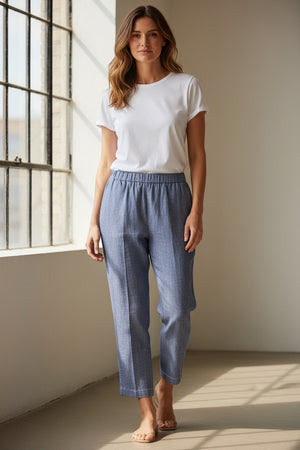 A person wears MEIMEIJ - DENIM COTTON PULL ON PANT: blue, straight-leg, cropped trousers with an elastic waist, subtle textured pattern, and relaxed fit. Made by MEIMEIJ from cotton. Photographed against a white background.