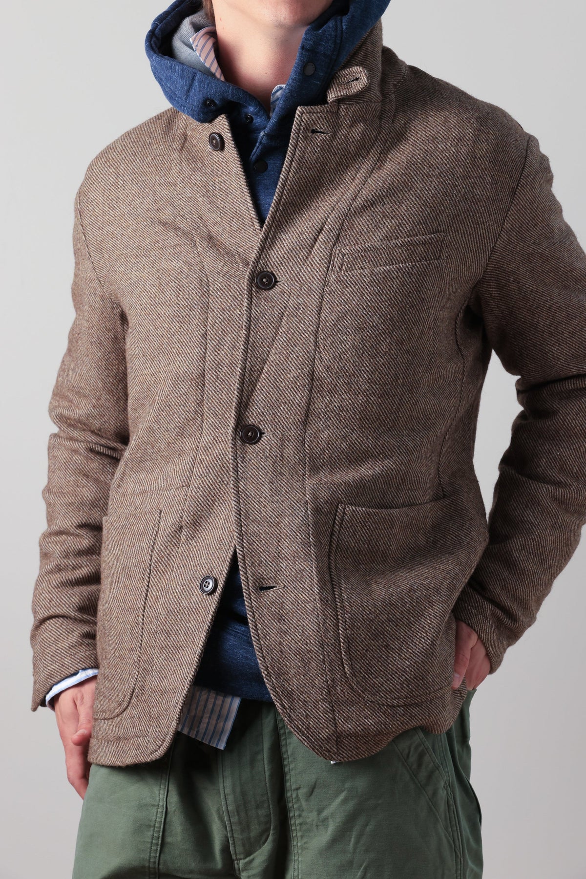 The RELWEN Heritage Trap Blazer in Brown and Blue Check features a brown and black plaid pattern, reminiscent of a classic check blazer, shown from the back with buttoned cuffs and a subtly wrinkled texture, laid flat on a white background.