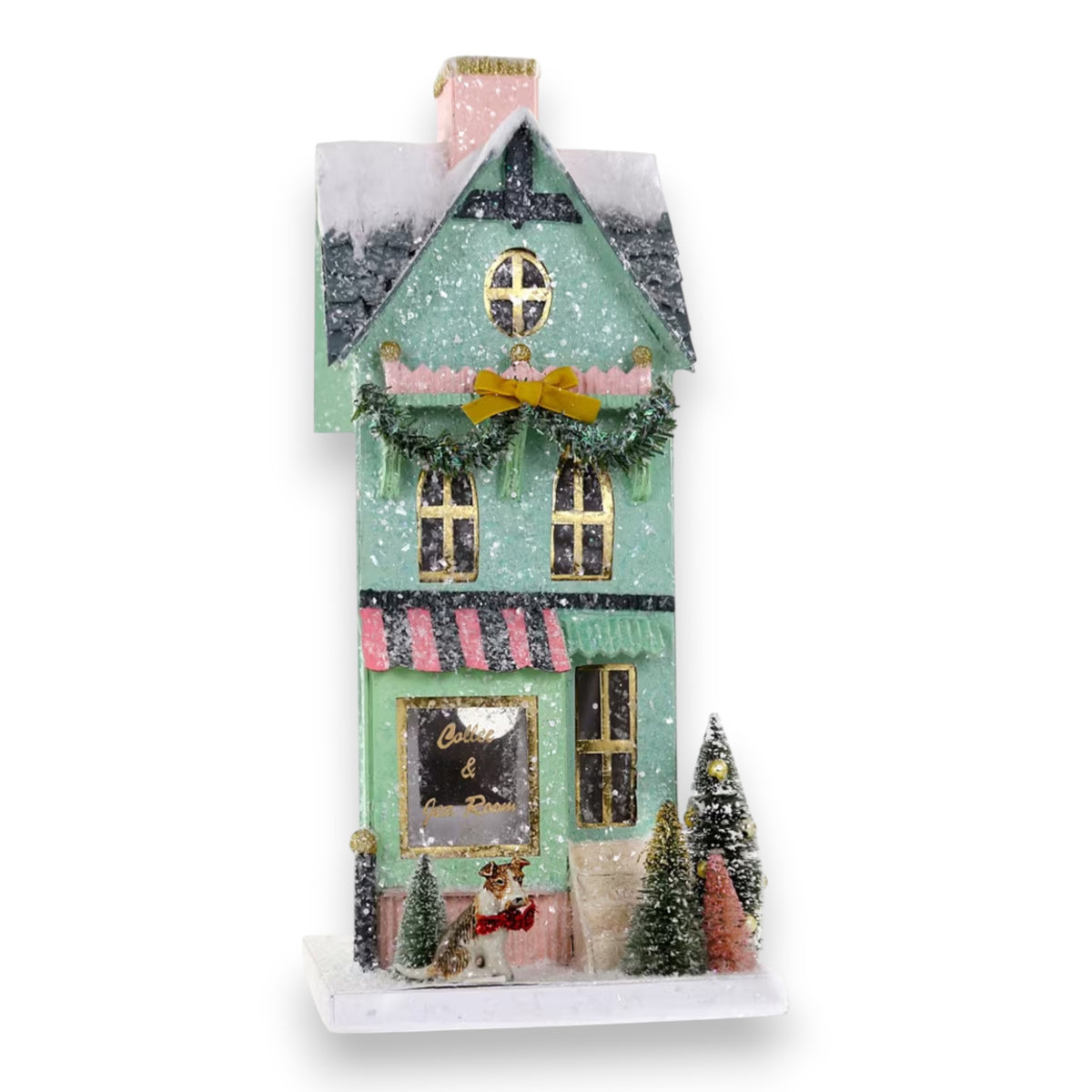 The CODY FOSTER TEA ROOM HOLIDAY HOUSE is a pastel green and pink, snow-dusted model with a wreath, small trees, gold bow, festive window display, and a dog figure—ideal for collectors or decor lovers.