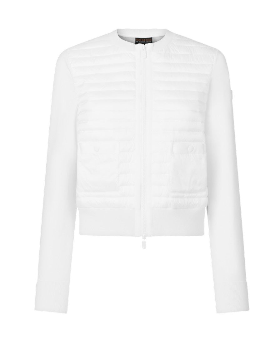 A woman with short gray hair stands against a white wall wearing the SAVE THE DUCK BRIONY LIGHTWEIGHT PUFFER—a cropped, quilted white jacket—paired with light gray pants and white sneakers. An ideal layering option for cooler days.