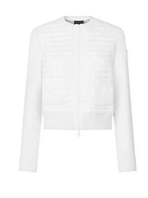 A woman with short gray hair stands against a white wall wearing the SAVE THE DUCK BRIONY LIGHTWEIGHT PUFFER—a cropped, quilted white jacket—paired with light gray pants and white sneakers. An ideal layering option for cooler days.