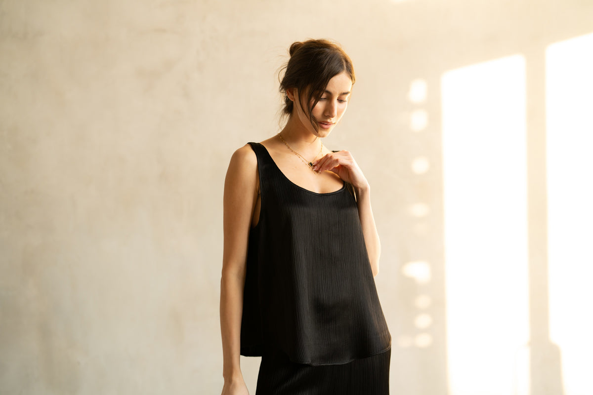 The ROSE &amp; CROWN SATIN RIBBED CAMI is a sleeveless, light beige top with a scoop neckline, shown on a white hanger against a plain background—a versatile wardrobe essential.