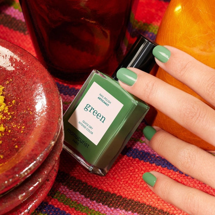 A bottle of MANUCURIST INC GREEN™ Nail Polish in the shade “Artichoke,” a green, quick-dry polish with intense color.