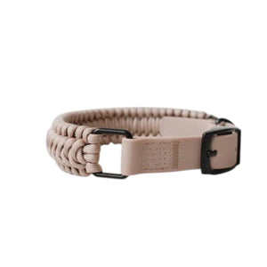 Two LAMBWOLF COLLECTIVE NEW JUPITER Dog Collars in small, one in beige and one in gray, are stacked on a light wooden surface against a plain, light-colored wall. Designed by LAMBWOLF COLLECTIVE, each collar combines cushioned comfort with sturdy durability, making them perfect for everyday wear.