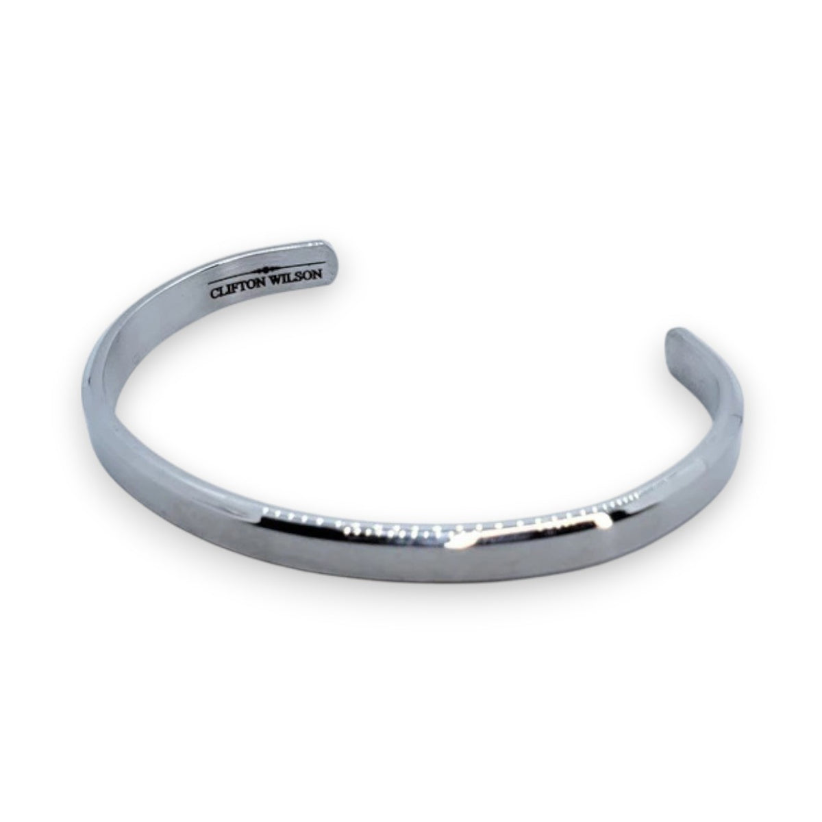 The CLIFTON WILSON - SILVER STAINLESS STEEL BANGLE is a minimalist, open-ended men's cuff featuring the brand engraved inside, shown against a white background for a refined accessory look.