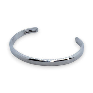 The CLIFTON WILSON - SILVER STAINLESS STEEL BANGLE is a minimalist, open-ended men's cuff featuring the brand engraved inside, shown against a white background for a refined accessory look.