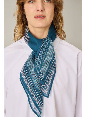 A detailed illustration of a cat and an owl sitting side by side on a branch, bordered by an intricate blue and white pattern, evokes the fine craftsmanship of the INOUI EDITIONS - CHOUETTE SQUARE SCARF IN BLUE by INOUI.