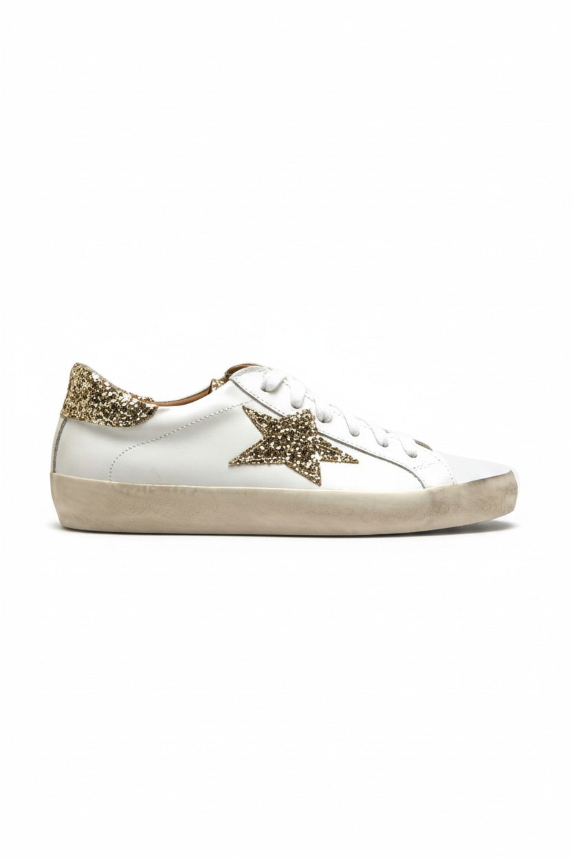 The MICHELE LOPRIORE GEMMA SNEAKERWITH PLATINUM STAR features a soft white leather upper, platinum glitter star and heel details, plus a slightly worn extra-light rubber sole, shown against a plain light background.