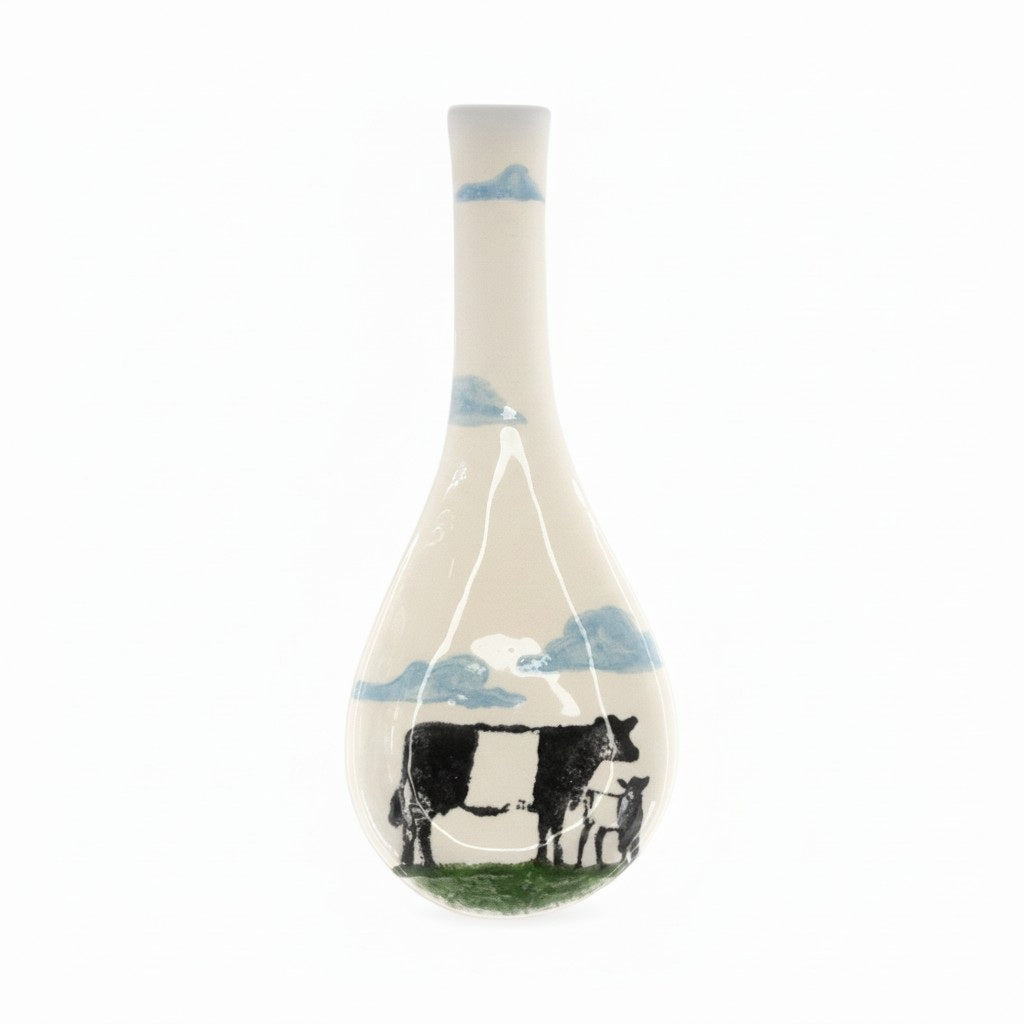The FEARRINGTON SIGNATURE COLLECTION - BELTIE SPOON REST BY VIETRI features a playful black and white Beltie cow design with a UFO beam—an eye-catching, quirky accent from VIETRI that brings Fearrington Village charm to your kitchen.