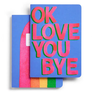 This E. FRANCES PAPER set includes two stitched OKLOVEYOUBYE notebooks, each 8.5 x 6 inches with soft covers, 26 ruled pages, and bold pink and green “OK LOVE YOU BYE” text on blue.