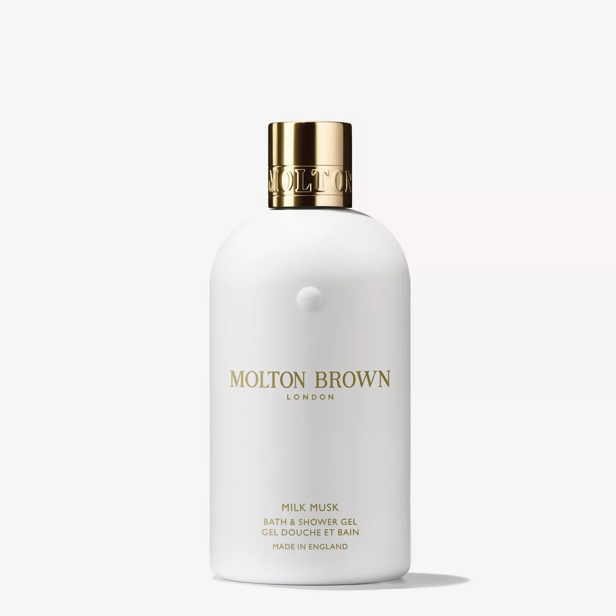 A white bottle of MOLTON BROWN - MILK MUSK BATH &amp; SHOWER GEL with a gold cap and minimalist gold text, highlighted against a plain white background, offers a luxurious blend of tonka bean and white musk. Brand: MOLTON BROWN.
