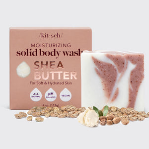 A bar of KITSCH - MOISTURIZING SHEA BUTTER BODY WASH with pink and white swirls rests on a pink box; this all-natural, pH balanced, vegan body wash leaves skin soft and hydrated.