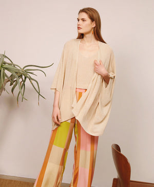 The MOMONI - DIVINA KNIT CARDIGAN is a chic brown, open-front piece with a draped, asymmetrical hemline. Crafted in Italy with wide sleeves, it's perfect as evening wear against a plain white backdrop.