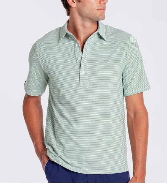 A man in a CRIQUET PERFORMANCE SPORT RANGE POLO IN HOBBY STRIPE - GATOR walks on a golf course, wearing blue pants, a white cap and glove, holding a club and smiling. Trees and a golf cart are visible in the background.