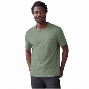 A person wears the MACK WELDON Heavyweight Slub Cotton Pocket T-Shirt in Cactus, a light olive green relaxed fit short-sleeve tee with a chest pocket, shown cropped to the upper torso against a plain white background.