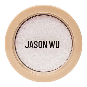 A small circular container of Jason Wu Beauty's "Ready to Shimmer Ethereal 1" eyeshadow. The cream eyeshadow is light-colored with an ethereal shimmer effect. The container features a beige-colored rim with the brand name "JASON WU BEAUTY" written in bold, black letters on the clear top.