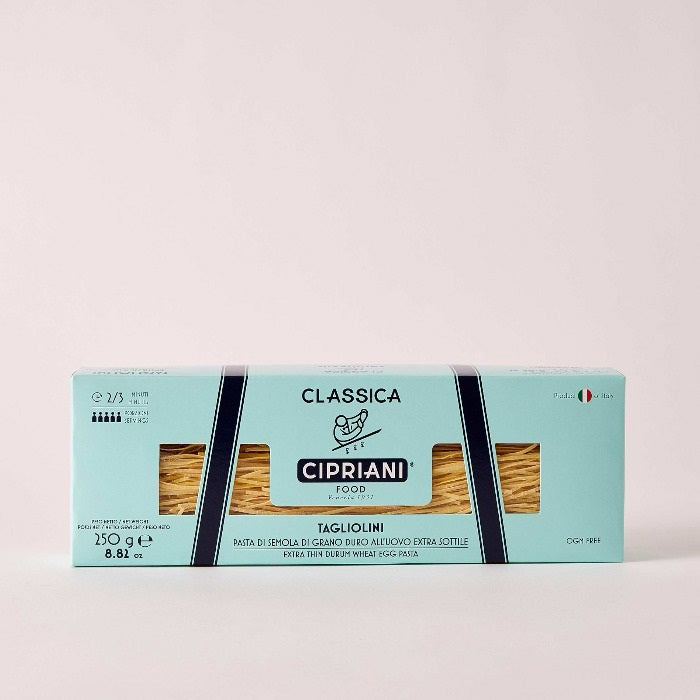 A rectangular light blue box labeled &quot;Atalanta Corporation&quot; containing Cipriani - Organic Tagliolini Egg Pasta made from premium durum wheat semolina is centered on a white background. The packaging features the brand name, weight (250g/8.82 oz), a small Italian flag, and the pasta is visible through a window in the packaging.