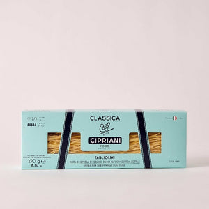 A blue box of Atalanta Corporation's Cipriani - Organic Tagliolini Egg Pasta displays thin egg pasta strands through a window, with Italian text, branding, and a small Italian flag—famed for classic Harry’s Bar dishes.