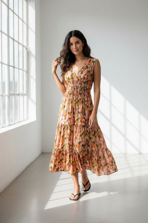 Wearing the HOPE FOR FLOWERS Tiered Peasant Maxi Dress in Garden Floral, featuring a sleeveless V-neck, shirred bodice, tiered skirt, and ruffled hem. Styled with black sandals against a plain white background.