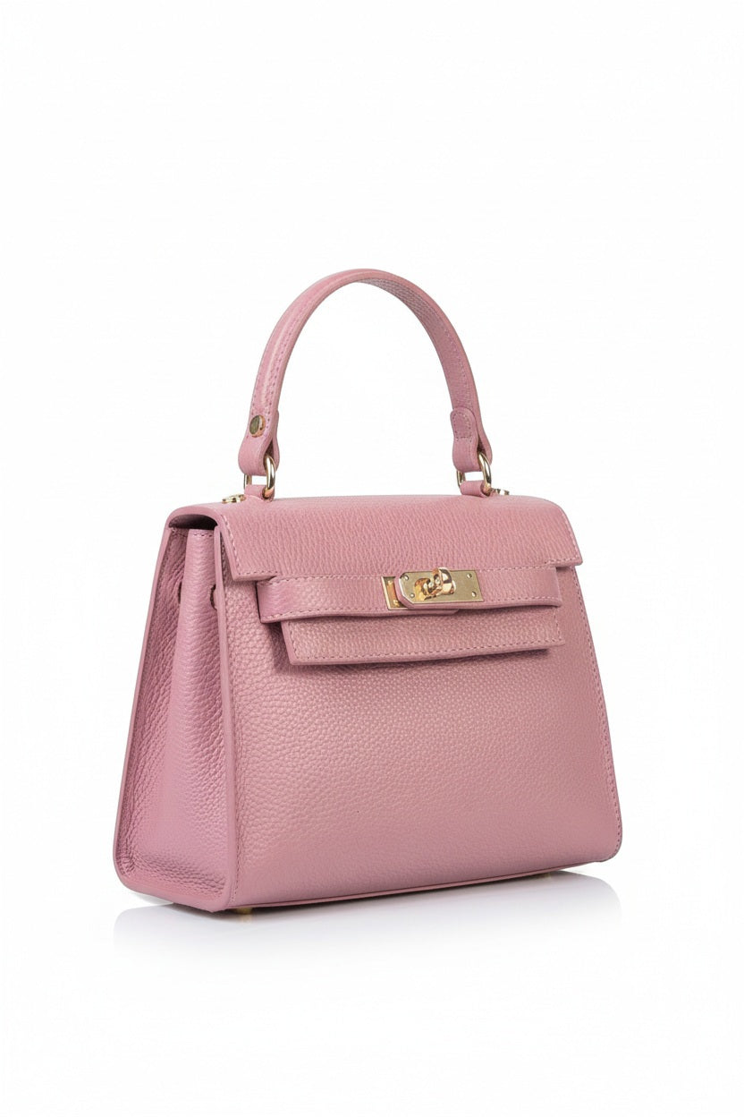The LE BORSETTE LEATHER SATCHEL BAG is a small, structured satchel-shaped handbag in light pink, featuring a gold clasp at the front. It boasts a single top handle, an adjustable shoulder strap, and two gold-tone hardware pieces on either side of the handle. The textured leather adds to its luxurious and elegant appearance against the plain white background.
