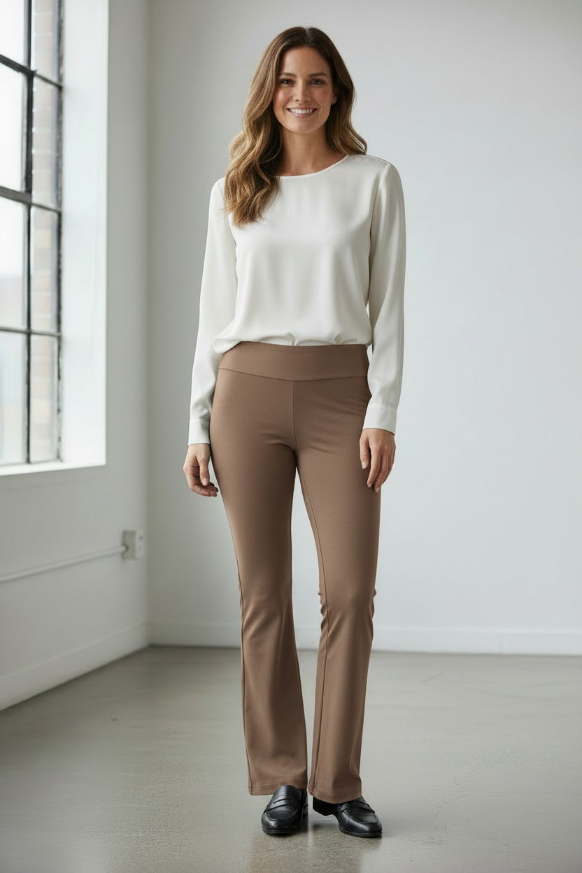 A person is wearing the MICROFIBER PULL ON PANT - LONG by KRAZY LARRY, INC in taupe microfiber and black pointed heels, standing against a plain white background. The pants have a fitted appearance, and the person's arms are cropped out of the image. Made in USA.