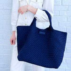 The PARKER & HYDE Oversized Woven Tote Bag is a hand-woven black tote with a matching pouch, both featuring a subtle crisscross pattern. The versatile tote has short handles and a sturdy texture, while the pouch includes a convenient zipper closure.