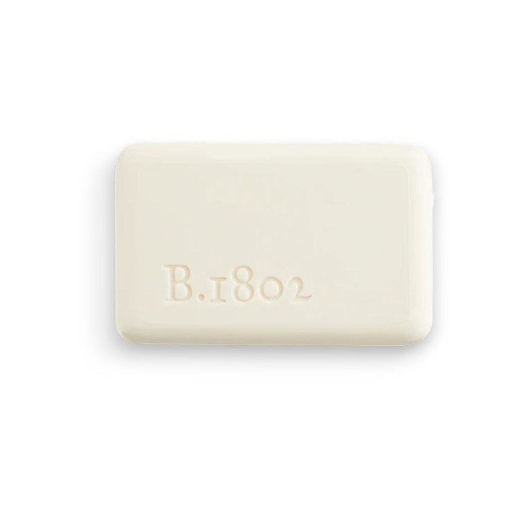 A bar of BEEKMAN - 9OZ. HONEY &amp; ORANGE BLOSSOM BAR SOAP from the BEEKMAN - STA ELEMENTS line is wrapped in decorative paper adorned with white and orange floral patterns. The label highlights that it is free from sulfates and parabens, featuring an illustration of a goat above the brand name, assuring you it&#39;s a moisturizing soap you can trust.