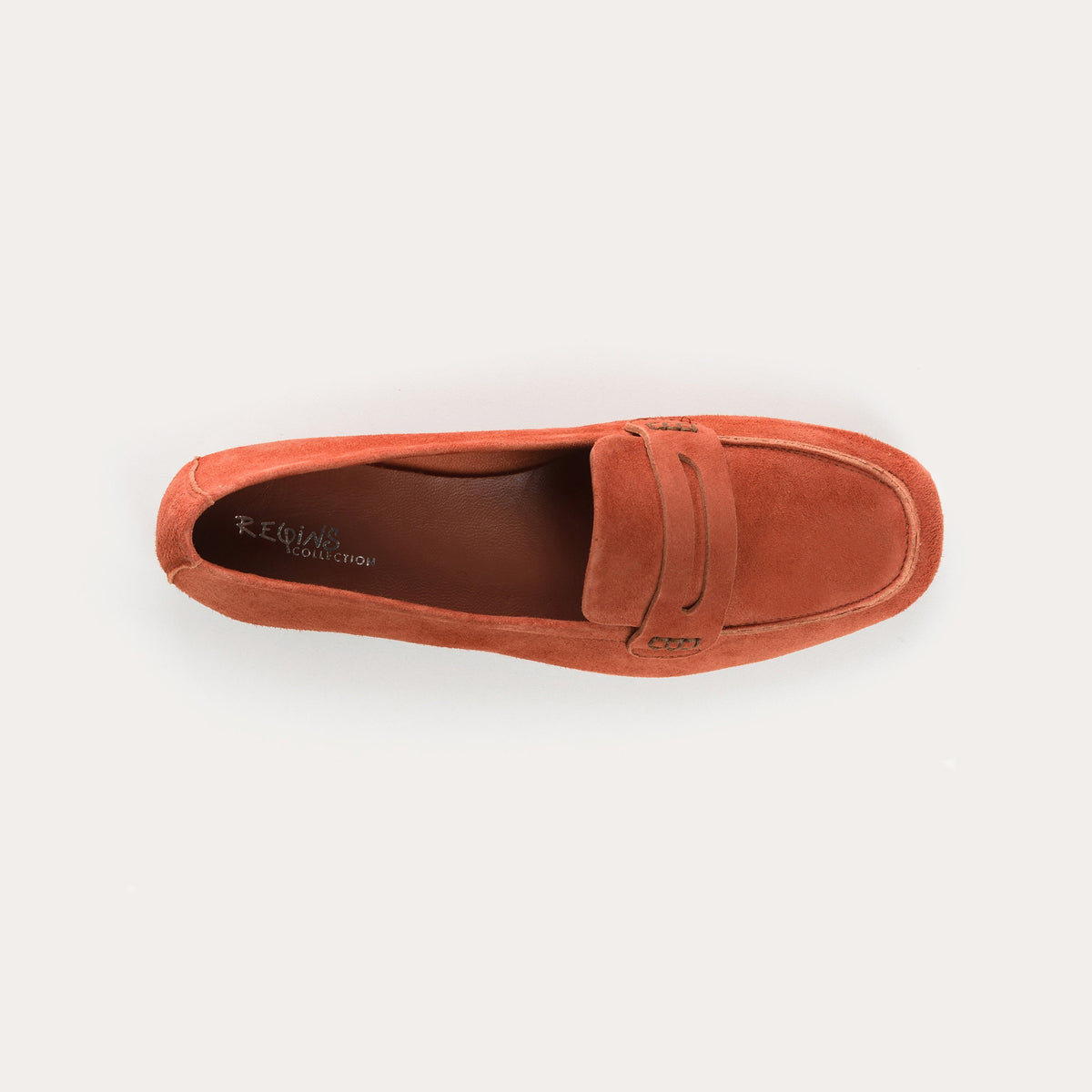 The REQINS HEMA Suede Loafer in Briques, a women’s classic loafer featuring a burnt orange suede upper, penny slot detail, and flat sole, is shown in profile against a white background.