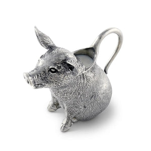 The VAGABOND HOUSE - PEWTER HAPPY PIG CREAMER, made from luxury-grade pewter, features pointed ears and detailed design. Its handle stretches from the back, revealing milk inside. This elegant piece by VAGABOND HOUSE sits on a plain white background.