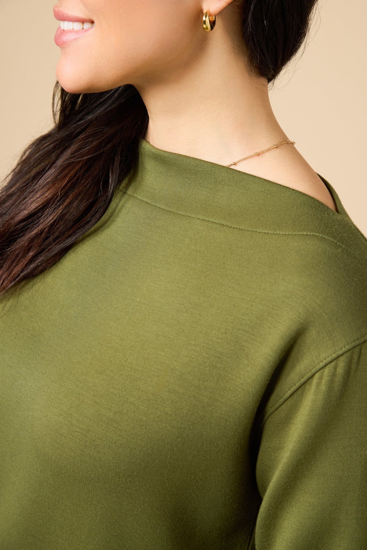 A woman wears a SOFTIES - DREAMTECH BOAT NECK WITH PINTUCK PANT SET in olive green, featuring a long-sleeve boat neck top and matching wide-leg pintuck pants.