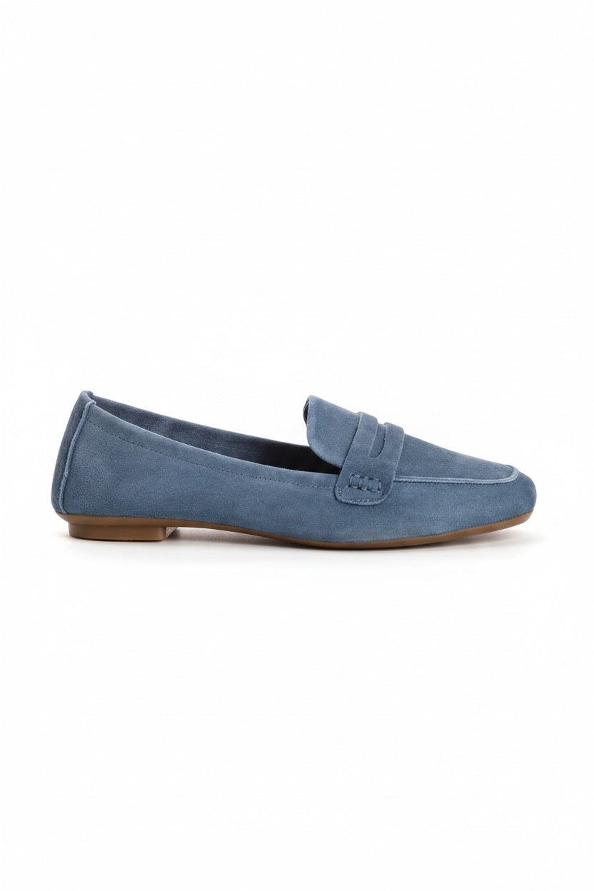 The REQINS - HEMA suede loafer in Blue Jean features a classic silhouette, minimalist design, penny strap, and brown soles, shown against a plain white background.