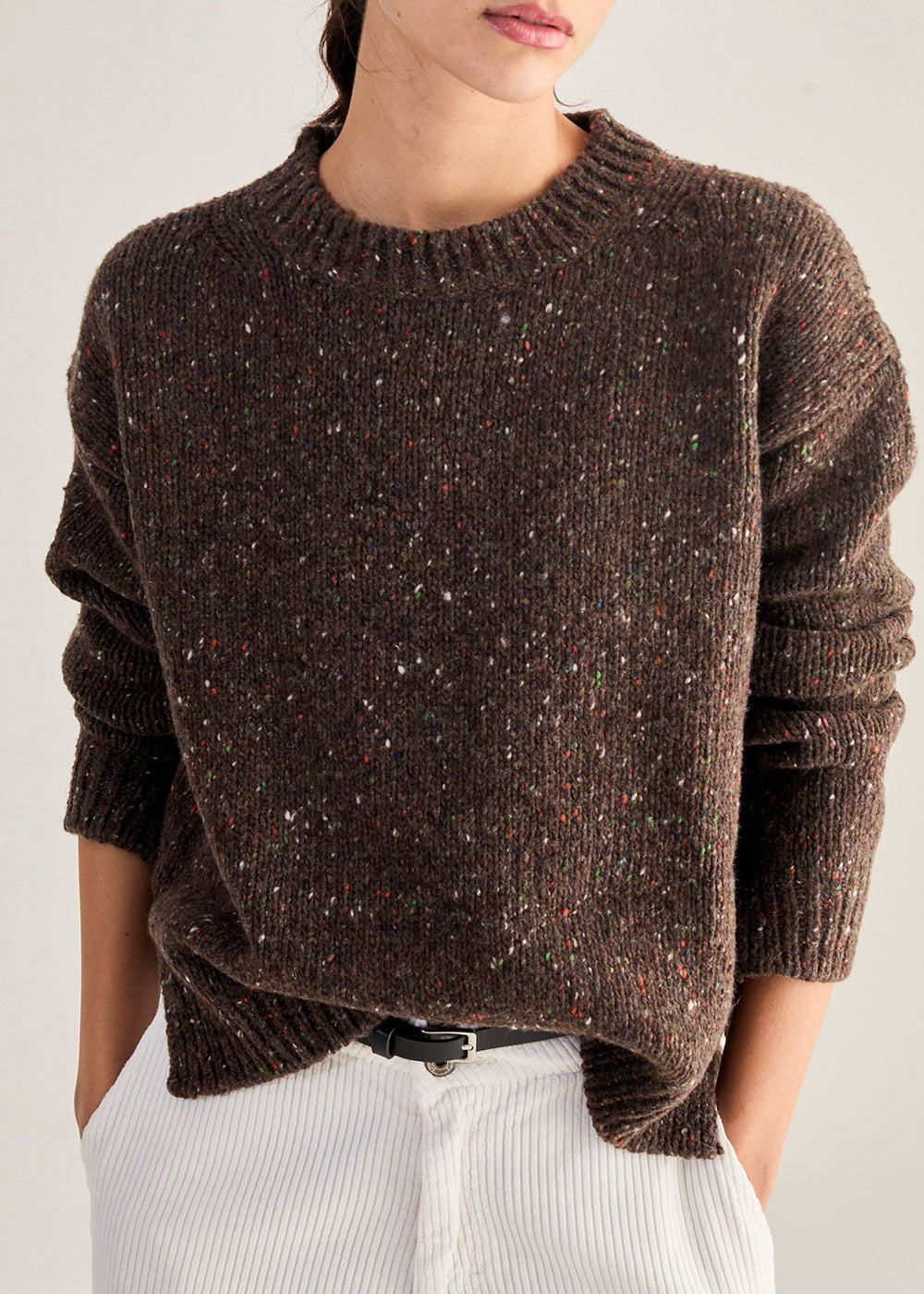 Close-up of the BASE MILANO - HEATHERED CREWNECK SWEATER, a textured, hand-knitted deep red virgin wool piece with multicolored flecks. Made in Italy by BASE MILANO.