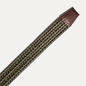 The WILL LEATHER GOODS - STRETCH BELT features a green, purple, and black braided design with full-grain leather accents by the silver buckle and tip, shown on a plain light background. Brand: WILL LEATHER GOODS.
