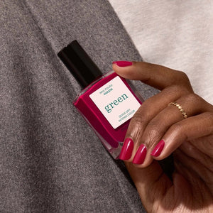 A bottle of MANUCURIST - GREEN™ Nail Polish in Violeta from MANUCURIST INC features a deep pinky purple shade, a black cap, and a label highlighting “green” and “quick dry intense color.”.