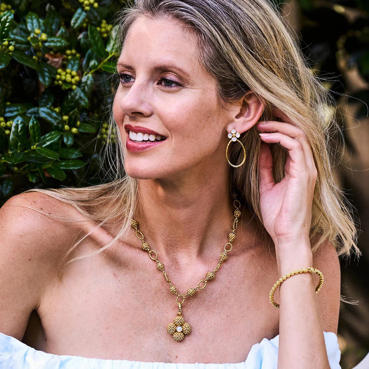 The CAPUCINE DE WULF - BERRY CLOVER DOUBLE SIDED PENDANT features a gold clover design with a textured, dotted surface and mother of pearl center. It includes a twisted loop for chain attachment.