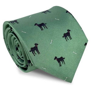 A rolled-up BIRD DOG BAY Black Lab Silk Tie in Mint, featuring a pattern of small black dogs and white bones evenly spaced across the woven silk, crafted in the signature style of BIRD DOG BAY.
