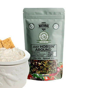 A package of TO MARKET - JUST HORSIN’ AROUND DIP MIX from TO MARKET- DIPS & SPREADS is displayed behind a white bowl of dip accompanied by two crackers. The package highlights zesty ingredients such as horseradish, garlic, and sun-dried tomatoes, and notes that it’s salt-free, gluten-free, and makes 4 cups.