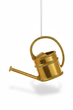 The ENGLISH WATERING CAN ORNAMENT by CODY FOSTER is a shiny gold piece with a curved handle and long spout, hanging from a thin metallic string—perfect for collectors and design lovers—displayed on a plain white background.