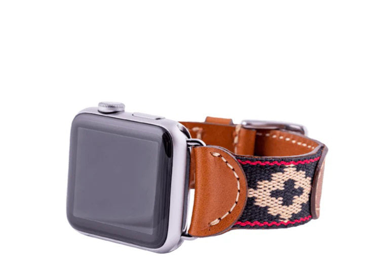 The LA MATERA CORBINA Apple Watch Band features an artisan-made brown leather band with a black woven strap and beige diamond pattern, displayed on a white background.
