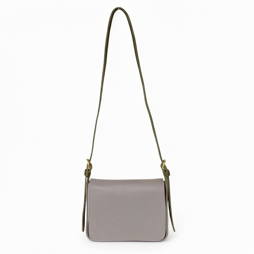 The OLIVEVE Genevieve Crossbody in Portobelo Italian buffalo cowhide is a compact, rectangular bag in light gray, featuring a long olive green strap and gold hardware, showcased against a plain white background.