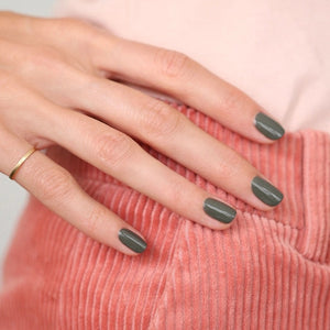 A bottle of MANUCURIST INC GREEN™ Nail Polish in Khaki, featuring a black cap and a label that reads “NAIL POLISH KHAKI, green, QUICK DRY INTENSE COLOR.” This vegan nail polish delivers quick-drying, intense color for a modern look.